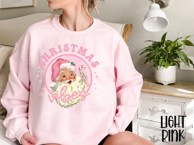 May include: Pink Christmas sweatshirt with a vintage Santa Claus illustration and the text "Christmas Vibes".