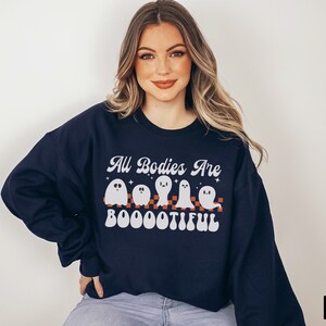 May include: A navy blue sweatshirt with a white graphic of ghosts and the text "All Bodies Are Boootiful".
