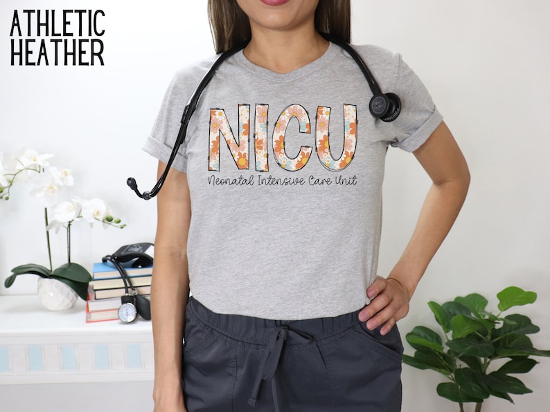 May include: A gray t-shirt with the word "NICU" in large, colorful letters with a floral pattern. The text "Neonatal Intensive Care Unit" is printed below the word "NICU".