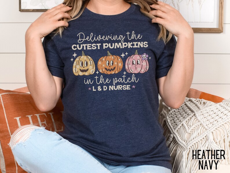 May include: Heather navy t-shirt with the text "Delivering the cutest pumpkins in the patch L&D Nurse". The shirt features three cartoon pumpkins in yellow, orange, and pink.