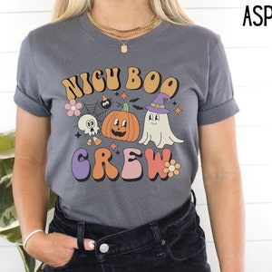 May include: A dark gray t-shirt with a retro-style graphic that says "NICU BOO CREW" with a pumpkin, ghost, and spider.