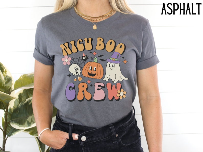 May include: A dark gray t-shirt with a retro-style graphic that says "NICU BOO CREW" with a pumpkin, ghost, and spider.
