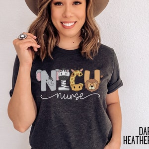 K&ouml;nnte beinhalten: Dunkelgraues T-Shirt mit einem Aufdruck von Tieren, die "NICU nurse" buchstabieren.