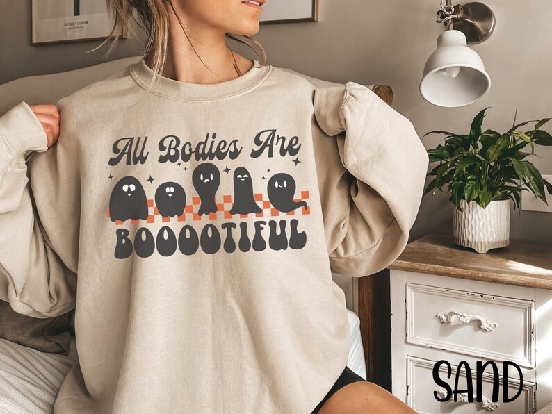 May include: A beige sweatshirt with a graphic of ghosts and the text "All Bodies Are Boootiful".