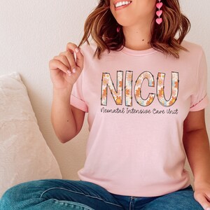 May include: Pink t-shirt with a floral design spelling out "NICU" and the text "Neonatal Intensive Care Unit" underneath.