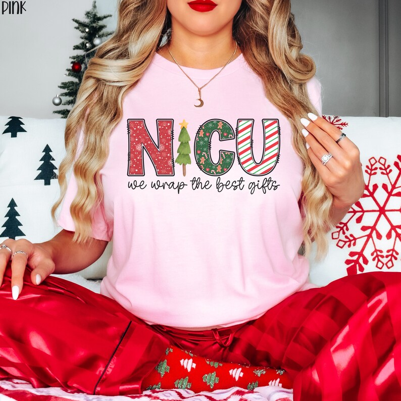 Puede incluir: Camiseta rosa con tem&aacute;tica navide&ntilde;a con el texto "NICU we wrap the best gifts" y un gr&aacute;fico de &aacute;rbol de Navidad verde.