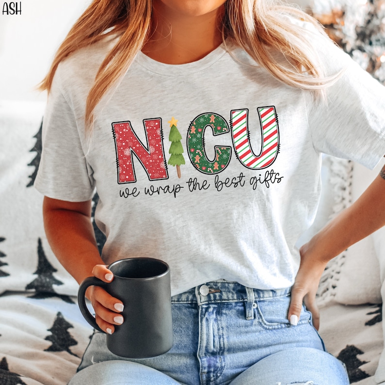 Puede incluir: Una camiseta blanca con un dise&ntilde;o rojo, verde y blanco que dice "NICU we wrap the best gifts".