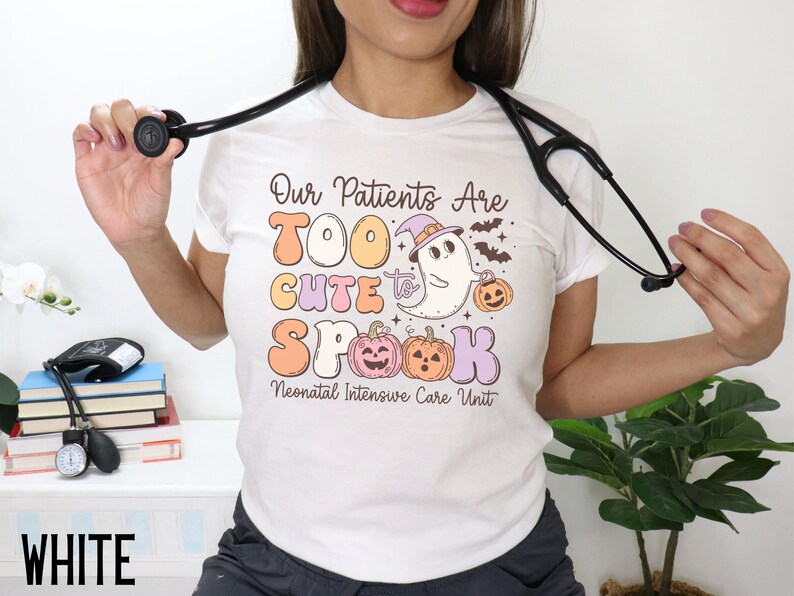 May include: White t-shirt with a Halloween-themed design that says "Our Patients Are Too Cute To Spook" with a ghost and pumpkins. The text "Neonatal Intensive Care Unit" is below the design.
