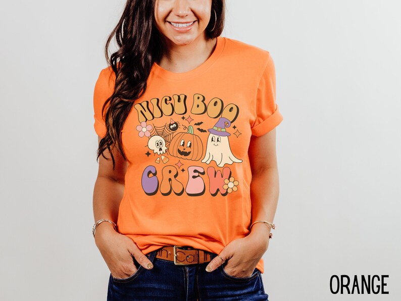 May include: Orange t-shirt with a retro-style graphic that says "Boo Crew" with a pumpkin, ghost, and other Halloween-themed imagery.