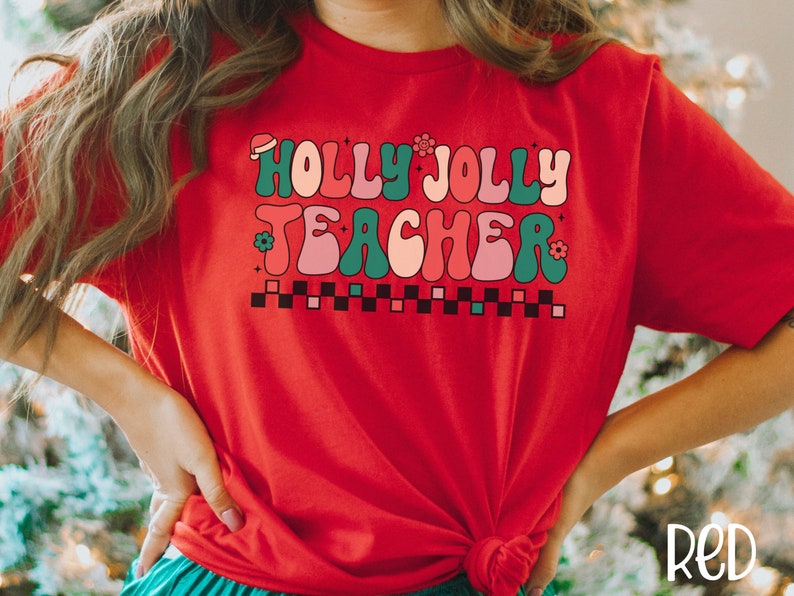 May include: Red t-shirt with a retro-style graphic that says "Holly Jolly Teacher" in green, pink, and white.
