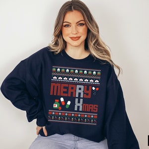 K&ouml;nnte beinhalten: Marineblauer Weihnachtspullover mit einem roten und wei&szlig;en "Merry Xmas"-Design mit einem Muster aus medizinischen Symbolen und Pillen.