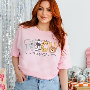 K&ouml;nnte beinhalten: Pinkes T-Shirt mit einer Grafik von Tieren, die "NICU nurse" buchstabieren.