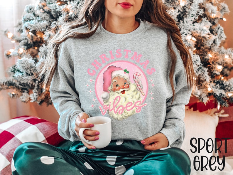May include: A gray sweatshirt with a pink circle graphic featuring a vintage Santa Claus illustration and the text "Christmas Vibes".