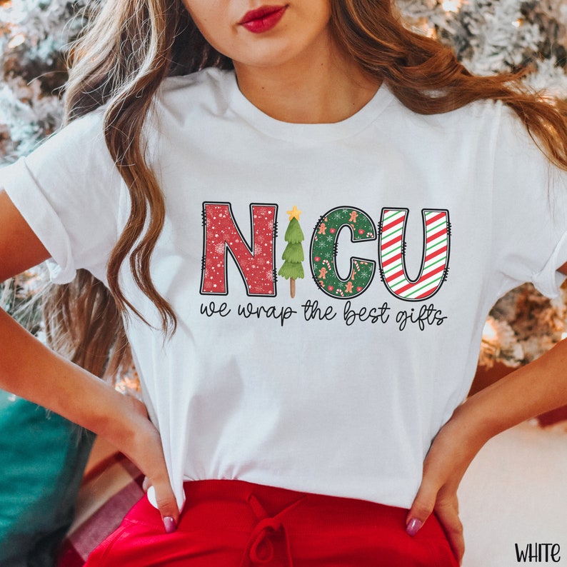 Puede incluir: Camiseta blanca con un dise&ntilde;o rojo, verde y blanco que dice "NICU we wrap the best gifts". El dise&ntilde;o presenta un &aacute;rbol de Navidad, copos de nieve y bastones de caramelo.