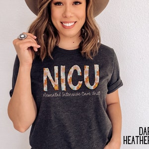 May include: A dark heather grey t-shirt with a floral design spelling out "NICU" and the text "Neonatal Intensive Care Unit".