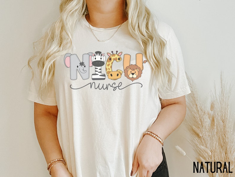K&ouml;nnte beinhalten: Ein wei&szlig;es T-Shirt mit einer Grafik von Tieren, die "NICU nurse" buchstabieren. Die Tiere sind ein Zebra, eine Giraffe, ein Elefant und ein L&ouml;we.