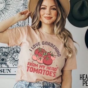 Może przedstawiać: R&oacute;żowy T-shirt z napisem "Uwielbiam ogrodnictwo od głowy do pomidor&oacute;w" i grafiką czerwonych pomidor&oacute;w.