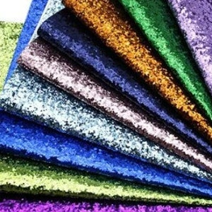 May include: A set of ten glitter fabric sheets in various colors, including purple, green, blue, and gold. The sheets are arranged in a fan shape, with the purple sheet on top.
