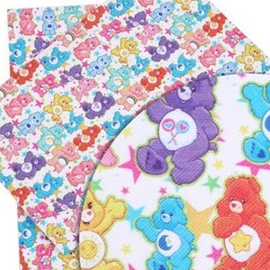 May include: A collection of colorful Care Bear-themed fabric pieces. The designs feature various Care Bears in different colors, surrounded by stars, on a white background. The fabric pieces are in a square and circular shape.