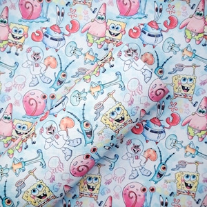 May include: A light blue patterned fabric featuring cartoon characters from the animated series SpongeBob SquarePants. The design includes SpongeBob, Patrick, Squidward, Mr. Krabs, Sandy, Plankton, and Gary, along with jellyfish and other aquatic elements.