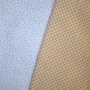 May include: Two fabric samples. One is white with a pattern of colorful sprinkles. The other is tan with a waffle pattern. Both fabrics are textured and appear to be suitable for crafting or sewing projects.