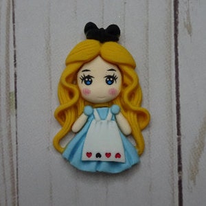 May include: A handcrafted figurine of Alice from Alice in Wonderland. The figurine features a light blue dress, white apron with heart details, and long, flowing yellow hair. A black bow sits atop her head. The figurine is set against a light wood grain background.
