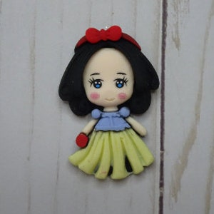 May include: A handcrafted Snow White figurine with black hair, blue eyes, and a red bow. The doll wears a blue top, a yellow skirt, and red gloves. The figurine is a charming representation of the classic fairytale character.
