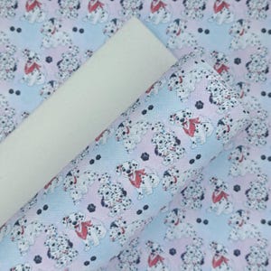 May include: A sheet of white faux leather with a sheet of blue and pink faux leather with a repeating pattern of Dalmatian dogs printed on it.