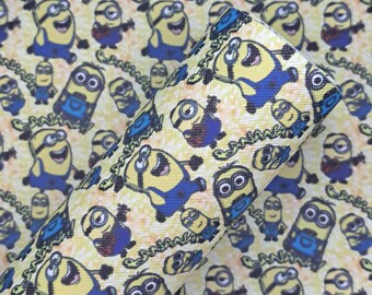 May include: Yellow and blue Minions pattern on a textured surface. The design features various Minion characters in different poses, set against a speckled background. The fabric is rolled, showcasing the repeating pattern.