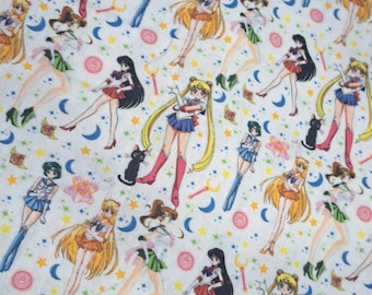 Może przedstawiać: Biała tkanina z powtarzającym się wzorem postaci z anime w strojach marynarskich. Postacie mają długie włosy i są otoczone księżycami, gwiazdami i magicznymi różdżkami. Kolorystyka obejmuje niebieski, czerwony, żółty i zielony.
