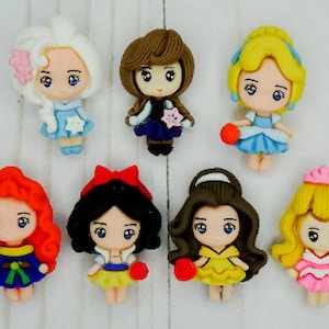 May include: Set of eight small, colorful, cartoon-style princess figurines. Each figurine is made of polymer clay and has a unique design and color scheme. The princesses are all wearing dresses and have large eyes and smiles.
