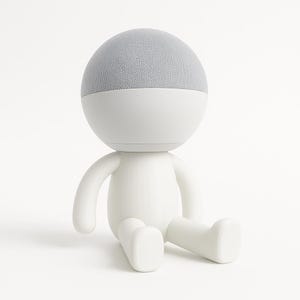 Peut inclure: Une figurine blanche de style cartoon avec un haut-parleur gris sur la tête. La figurine est assise les jambes croisées.