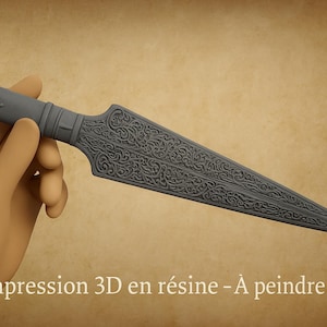 Può includere: Un pugnale grigio con intricati disegni floreali e di teschio sull'impugnatura e sulla lama. Il testo "Impression 3D en résine - À peindre" è visibile. Il pugnale è tenuto in una mano.