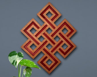 May include: Wooden wall art featuring a geometric Endless Knot design with a reddish-brown interior and a natural wood-tone frame. The artwork is mounted on a gray wall, with a potted plant and colorful planters in the foreground.