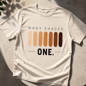 以下が含まれることがあります： 「MANY SHADES」の文字と、薄いベージュから濃い茶色までの垂直な色の見本が並び、その下に「ONE.」と書かれたクリーム色のTシャツ。ニュートラルな表面に表示されています。
