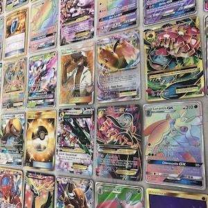 May include: A collection of Pokemon trading cards featuring various characters and illustrations. The cards are arranged in rows and columns, with some cards featuring holographic effects.