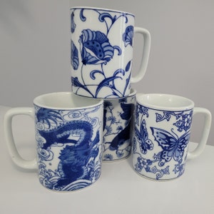 May include: Four ceramic mugs with blue and white designs. One mug features a dragon, another a fish, another a butterfly, and the last a floral design.