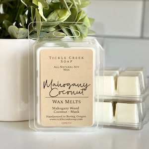 May include: A wax melt in a clear plastic container with a brown label that reads "TICKLE CREEK SOAP", "ALL NATURAL SOY WAX", "Mahogany Coconut", "WAX MELTS", "Mahogany Wood Coconut - Musk", "Handpoured in Boring, Oregon", "www.ticklecreeksoap.com", and "2.5 OZ/70g".