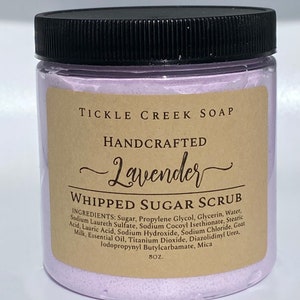 May include: A purple jar of lavender-scented whipped sugar scrub with a black lid. The jar is labelled "Tickle Creek Soap" and "Handcrafted Lavender Whipped Sugar Scrub". The ingredients are listed on the label.