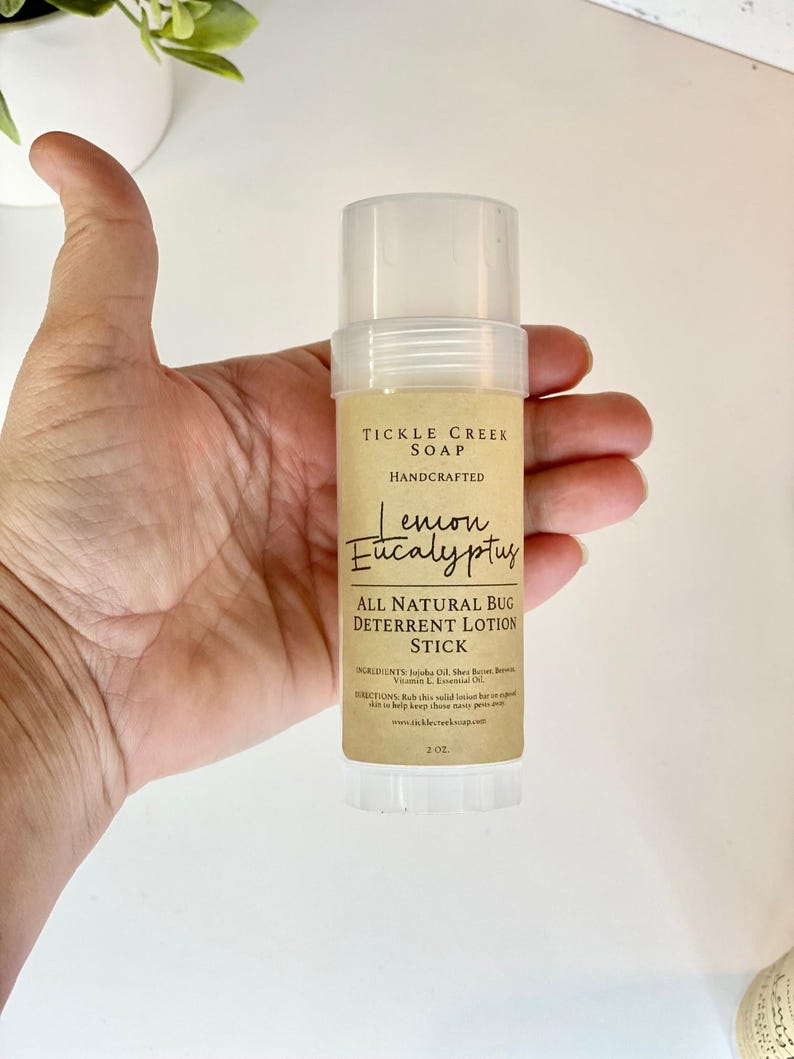 May include: A brown and white label on a clear plastic tube reads "Tickle Creek Soap Handcrafted Lemon Eucalyptus All Natural Bug Deterrent Lotion Stick 2 oz".