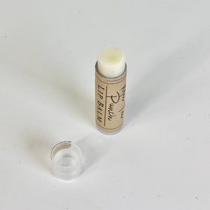 May include: A brown tube of lip balm with the text "Lip Balm" and "Punch" written on it. The lip balm is white and the tube is partially open.