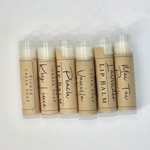 May include: Six small tubes of lip balm with brown paper labels. The labels have the words "Lip Balm" and different flavors: "Mai Tai Punch", "Lavender", "Vanilla", "Peach", "Key Lime", and "Tickle Creek Soap".