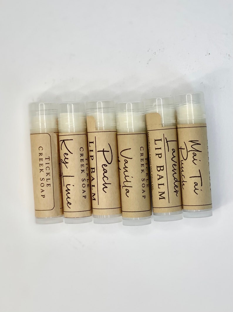 May include: Six small tubes of lip balm with brown paper labels. The labels have the words "Lip Balm" and different flavors: "Mai Tai Punch", "Lavender", "Vanilla", "Peach", "Key Lime", and "Tickle Creek Soap".