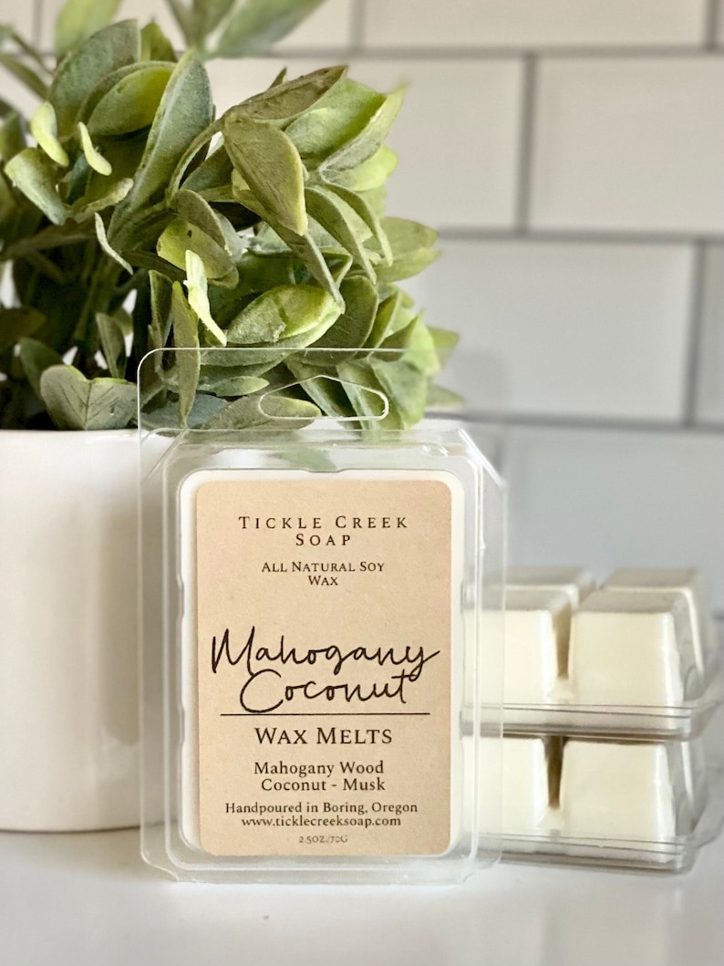 May include: A wax melt in a clear plastic container with a brown label that reads "TICKLE CREEK SOAP", "ALL NATURAL SOY WAX", "Mahogany Coconut", "WAX MELTS", "Mahogany Wood Coconut - Musk", "Handpoured in Boring, Oregon", "www.ticklecreeksoap.com", and "2.5 OZ/70g".