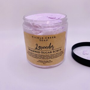 May include: A glass jar of lavender whipped sugar scrub with a brown label that reads "Tickle Creek Soap Lavender Whipped Sugar Scrub". The label lists the ingredients and instructions for use. The jar is 8 oz.