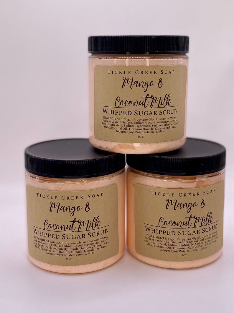 May include: Three jars of mango and coconut milk whipped sugar scrub. The jars are labeled "Tickle Creek Soap" and have a peach colored scrub inside. Each jar is 8 oz.