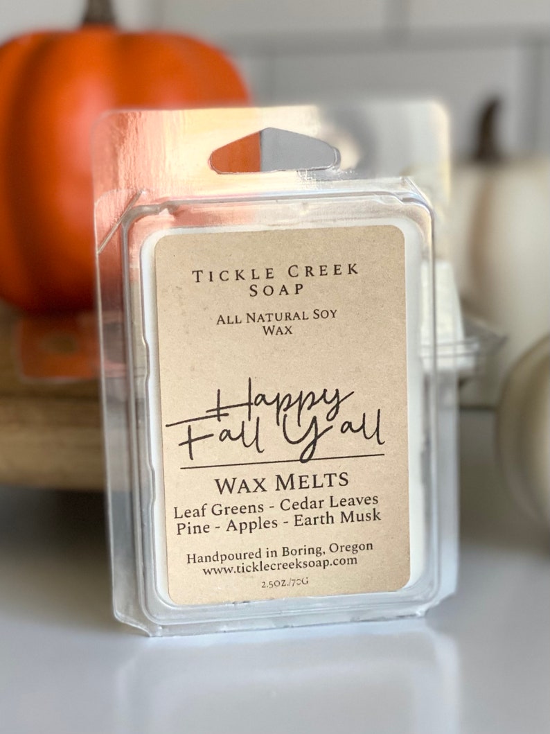 May include: A small clear plastic container with a brown label that reads "Tickle Creek Soap, All Natural Soy Wax, Happy Fall Y'all, Wax Melts, Leaf Greens - Cedar Leaves, Pine - Apples - Earth Musk, Handpoured in Boring, Oregon, www.ticklecreeksoap.com, 2.5 oz/70g".
