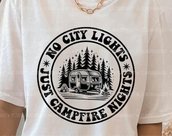 May include: A white t-shirt featuring a black graphic design of a camper van in a forest with the text "Just No City Lights* Just Campfire Nights*"