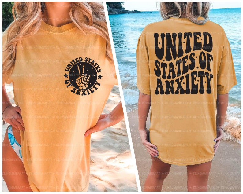 Peut inclure: Un t-shirt jaune avec un imprim&eacute; graphique noir qui dit "United States of Anxiety" avec un signe de paix et des mains de squelette. Le dos du t-shirt a le m&ecirc;me texte dans une police r&eacute;tro.