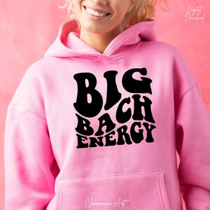May include: Pink hoodie with a black graphic that says "BIG BACH ENERGY" in a retro font.